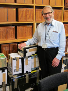 Ted Buttrey vor einem Stapel Kataloge, wie er sie an die numismatischen und historischen Institute der Welt verschickt. Die von Sammlern und Münzhandlungen kostenlos zur Verfügung gestellte Exemplare versendet er häufig auf eigene Kosten. Foto: Ursula Kampmann, Cambridge Januar 2011.