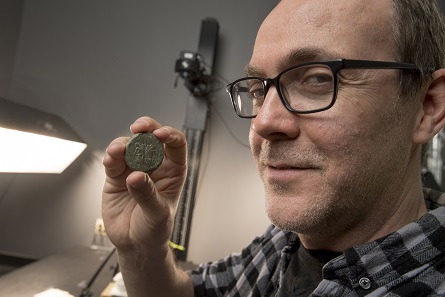 Rick Hale, who has spent the past several years digitizing the Badian Collection of Coins of the Roman Republic, examines one of his coins. Photo: Nick Romanenko, Rutgers University.