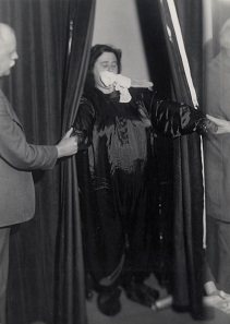 Helen Duncan emerging from curtains with ‘ectoplasm’ – her hands holding those of others at the séance. Edinburgh, 1933. Photograph © Senate House Library, University of London.